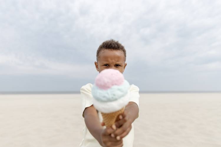 Kid holding ice cream cone on beach